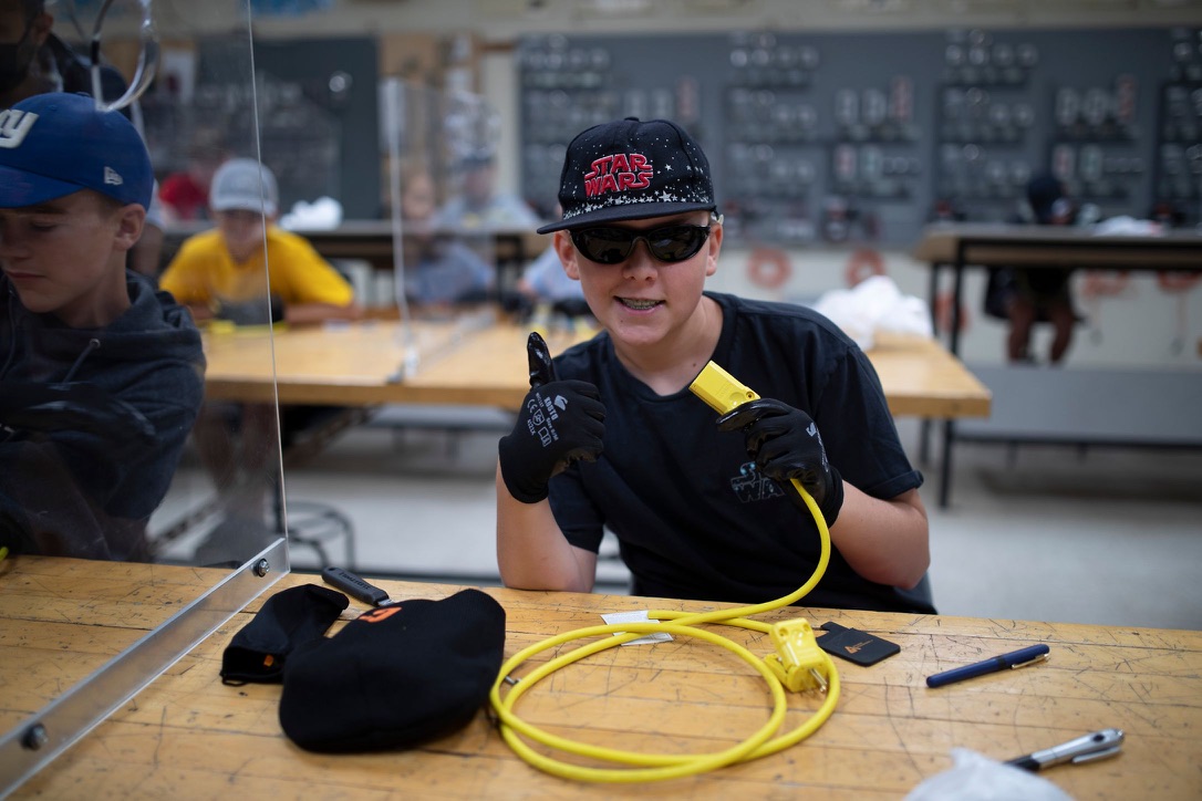 Student displaying a completed extension cord during an electrical summer camp