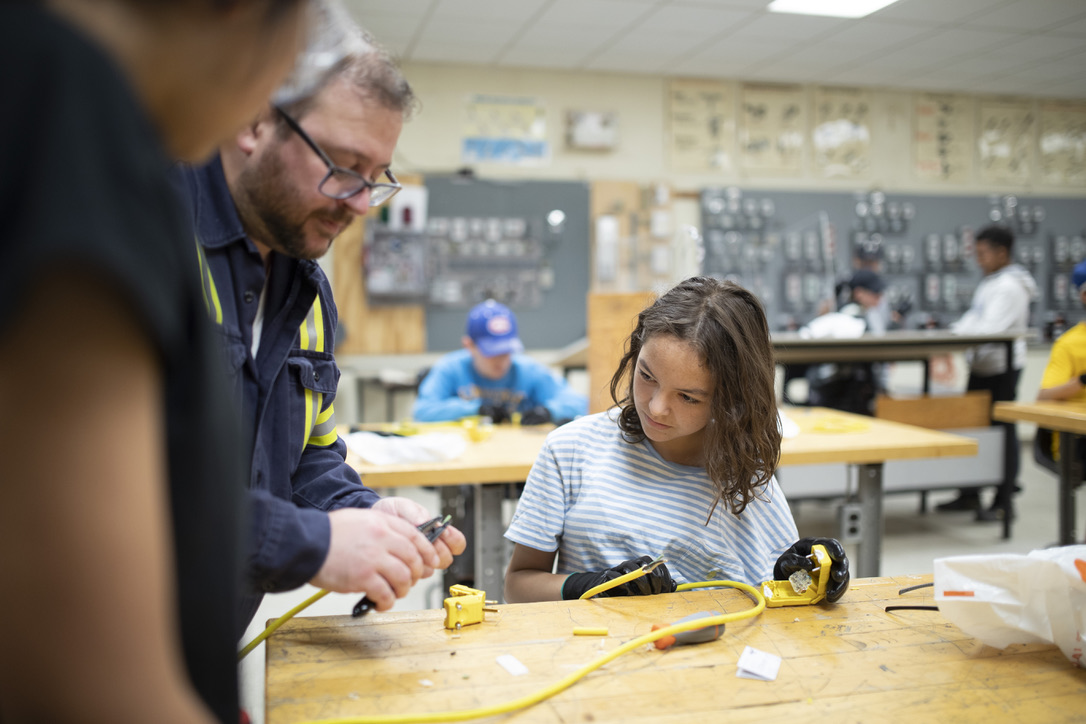 Volunteer instructor supporting a student with safe hand-tool use